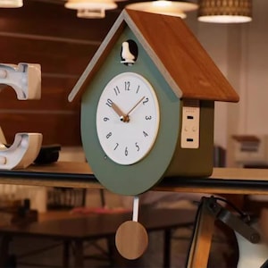 May include: A green and brown wooden birdhouse clock with a white face and black hands. The clock has a small bird on the roof and a pendulum.