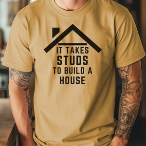 May include: A mustard yellow t-shirt with a black graphic of a house with the text "It takes studs to build a house".