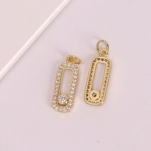 May include: Two gold-colored rectangular pendants with a central open space. The pendants are encrusted with small, clear crystals around the edges and feature a larger crystal in the center. Each pendant has a small loop at the top.