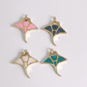 Puede incluir: Cuatro colgantes dorados con forma de manta raya. Cada colgante presenta un color diferente: rosa, azul, blanco y turquesa. Los colgantes tienen una superficie texturizada y un pequeño lazo en la parte superior para sujetar una cadena o cordón.