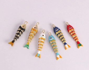 May include: Six colorful fish-shaped charms with gold-tone loops for jewelry making. The charms are painted in various colors, including black, gold, blue, red, and white, with detailed scale patterns and fins.