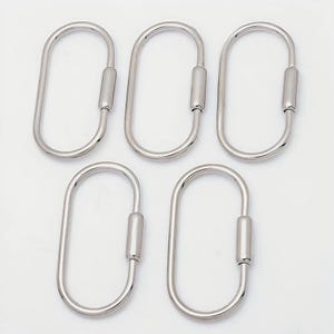 May include: Five silver-toned metal oval carabiner rings arranged in a group. Each ring features a smooth, continuous loop design with a spring-loaded gate mechanism on one side, allowing the ring to open and close for attaching various items.