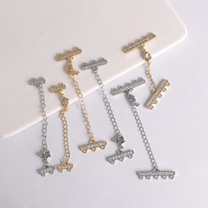 May include: A selection of gold and silver-toned jewellery extenders. Each extender has a small chain, a lobster clasp, and decorative bars embellished with tiny, clear crystals. These extenders are designed to lengthen necklaces or bracelets.