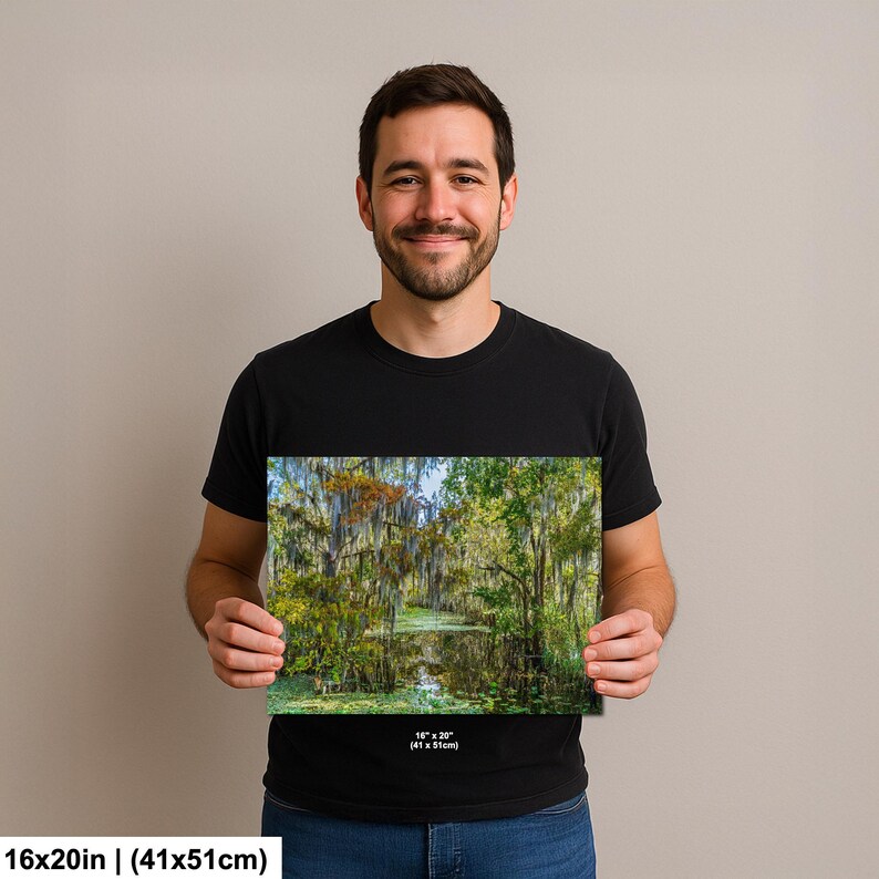 A man is holding a framed print of a forest scene, smiling and posing for the camera.