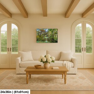 a cozy living room with a large window overlooking a lush green forest. The room is furnished with a white sofa, a wooden coffee table, and a vase of white flowers. The walls are painted in a light color, and the ceiling features wooden beams. A painting of a forest scene hangs on the wall, adding a touch of nature to the space.