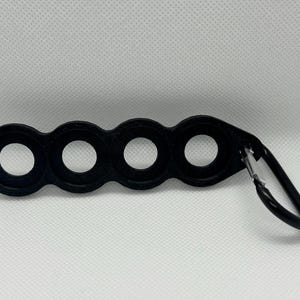 May include: Black plastic key chain with four round loops and a silver metal carabiner.