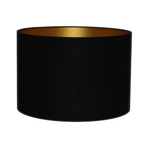 Peut inclure: Un abat-jour cylindrique de forme tambour avec un revêtement extérieur en tissu noir mat uni et une doublure intérieure contrastante en métal doré. Le design est simple et circulaire, offrant un profil épuré pour un luminaire.