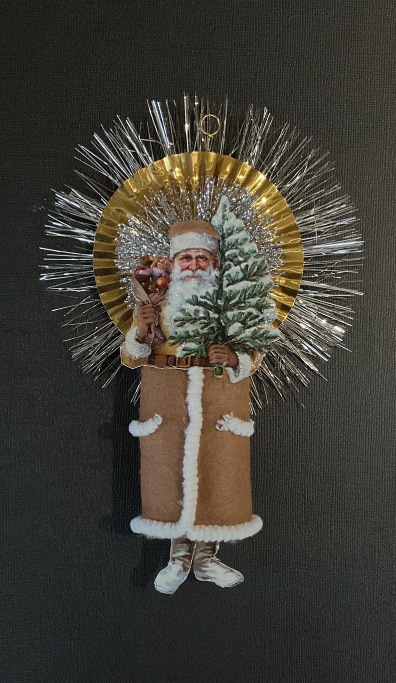 May include: A vintage Christmas ornament featuring a Santa Claus figure holding a small tree and a bag of gifts. The ornament is made of paper and fabric and is decorated with a gold and silver tinsel halo.