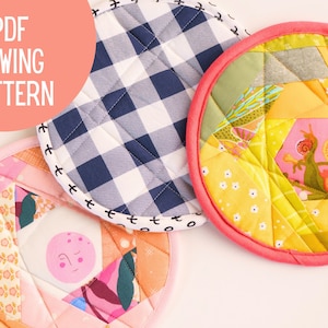 Puede incluir: Tres agarraderas de olla acolchadas de colores, una con un patrón de cuadros azules y blancos, otra con un patrón floral rosa y naranja, y otra con un patrón geométrico amarillo y verde. Las agarraderas de olla son todas redondas y tienen un ribete blanco alrededor del borde.