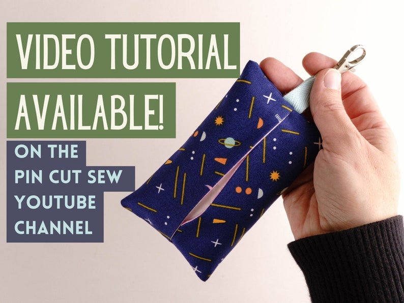 Pode incluir: Uma pequena bolsa de tecido azul com fecho de correr e um porta-chaves. A bolsa tem um padr&atilde;o colorido de estrelas, planetas e formas geom&eacute;tricas. O texto "VIDEO TUTORIAL AVAILABLE! ON THE PIN CUT SEW YOUTUBE CHANNEL" &eacute; vis&iacute;vel no lado esquerdo da imagem.