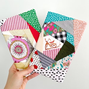 May include: Two colorful patchwork fabric pouches with geometric patterns. The pouches are made of different fabrics with various prints, including polka dots, stripes, floral designs, and checkered patterns.