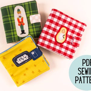 Puede incluir: Tres libros de tela con diferentes diseños. Uno es a cuadros verdes con un cascanueces, otro a cuadros rojos y blancos con una muñeca, y el tercero es amarillo con un logotipo de Star Wars.