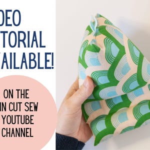 May include: A green and blue patterned fabric pillow with a triangular shape. The pillow is being held by a hand. The text "VIDEO TUTORIAL AVAILABLE! ON THE PIN CUT SEW YOUTUBE CHANNEL" is visible in the image.