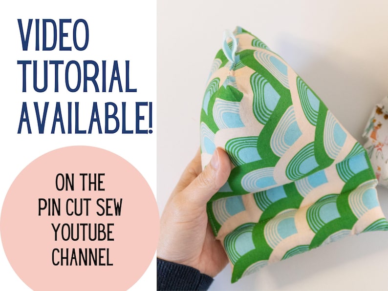 May include: A green and blue patterned fabric pillow with a triangular shape. The pillow is being held by a hand. The text "VIDEO TUTORIAL AVAILABLE! ON THE PIN CUT SEW YOUTUBE CHANNEL" is visible in the image.
