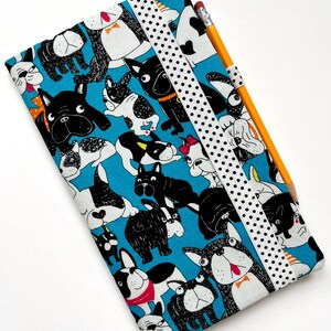 May include: A blue fabric pencil case with a black and white polka dot ribbon closure. The case is covered in a pattern of black and white cartoon French Bulldogs.
