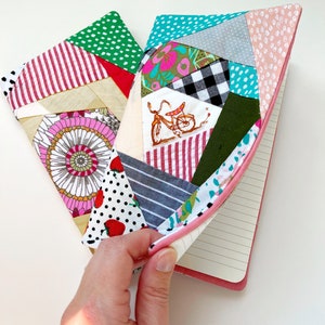 May include: A pink and green patchwork notebook cover with a bicycle design. The cover is made of different fabrics with various patterns, including polka dots, stripes, and floral prints.