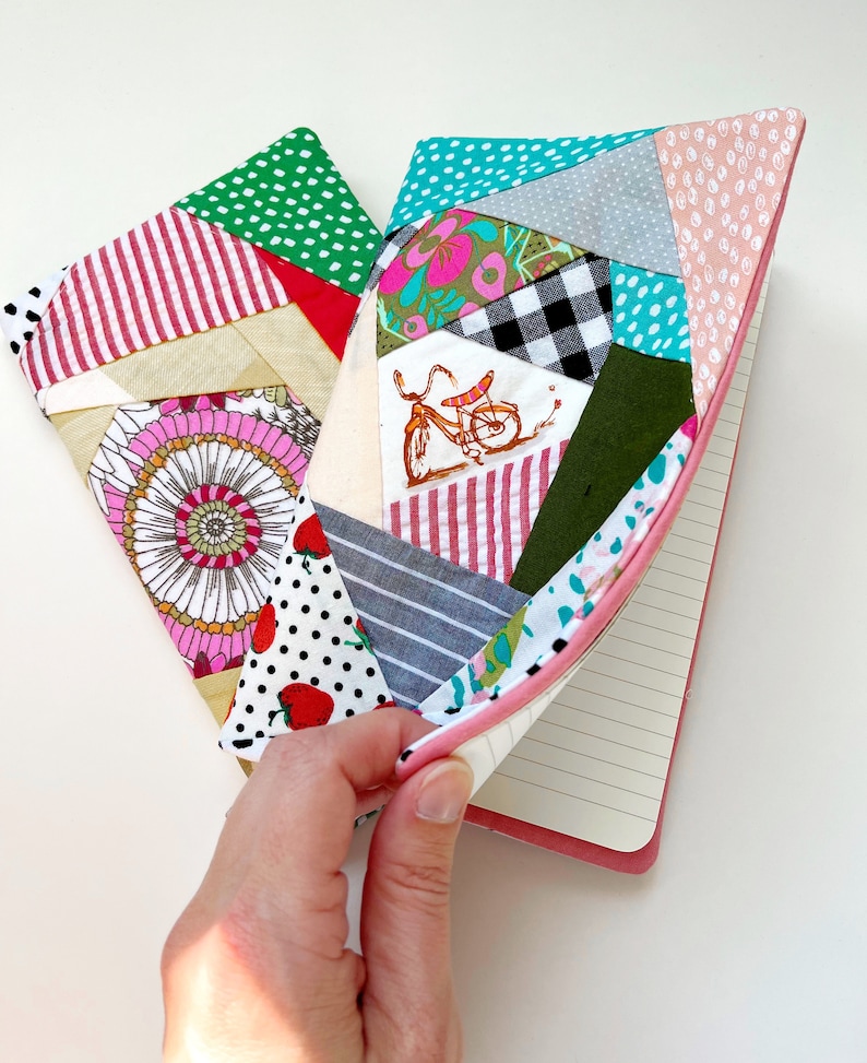 May include: A pink and green patchwork notebook cover with a bicycle design. The cover is made of different fabrics with various patterns, including polka dots, stripes, and floral prints.
