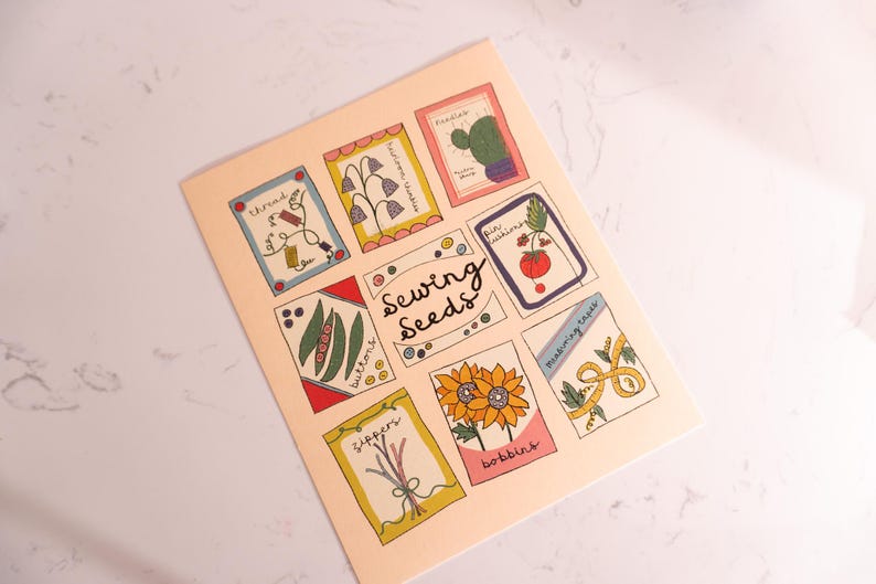 May include: A light peach-coloured print featuring illustrated sewing-themed images. The print includes images of thread, buttons, zippers, sunflowers, and other sewing notions. The words "Sewing Seeds" are written in the centre of the print.