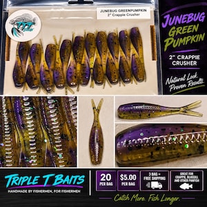 May include: A pack of 2-inch Crappie Crusher fishing lures in a Junebug Green Pumpkin colorway. The soft plastic baits feature a purple and olive green body with black and iridescent glitter flecks, a segmented ribbed texture, and a split tail design.