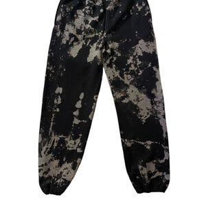 Op de afbeelding: Zwarte sweatpants met een wit splatter paint ontwerp.