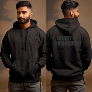 May include: Black hoodie with a front kangaroo pocket and a drawstring hood. The front features an embroidered "XO" design. The back of the hoodie displays the text "HURRY UP TOMORROW" in a bold, block font. The hoodie is made of a soft material.
