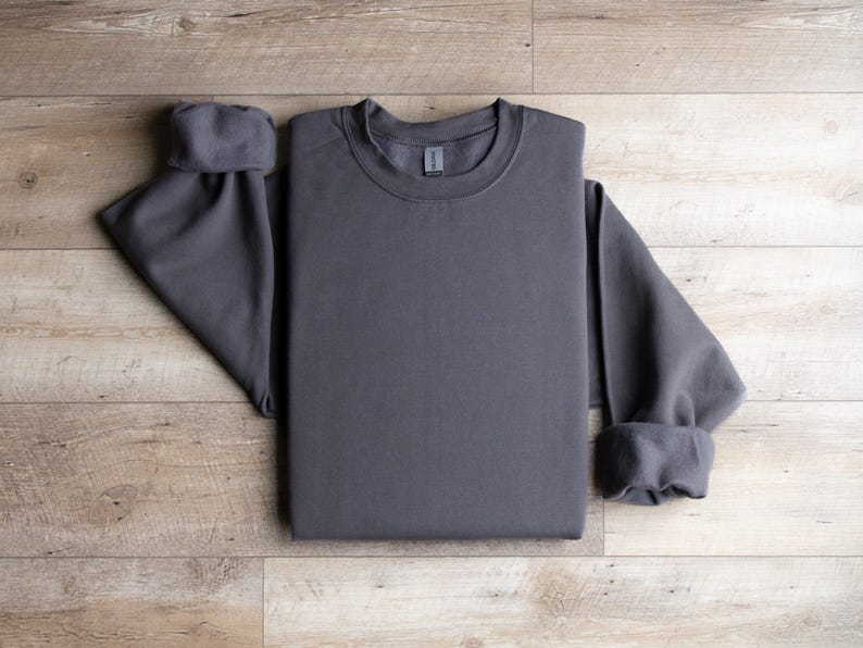 Puede incluir: Una sudadera gris antracita doblada sobre una superficie de madera.