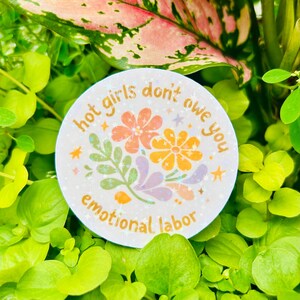 Round “Hot girls don’t owe you emotional labor” sticker displayed among lush green plants. Features retro-inspired floral illustrations in warm pastel tones with a bold feminist boundary-setting message. Ideal mental health, self-care, women’s empowerment, therapy, burnout recovery, and emotional wellness sticker for decorating laptops, water bottles, journals, Kindles, planners, and more.