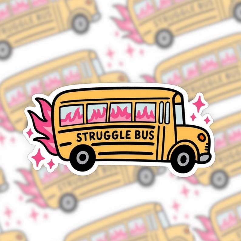 A hand-drawn sticker features a classic yellow school bus with pink flames coming out the back and the words “STRUGGLE BUS” written across the side in bold, black lettering. The bus windows are filled with pink fire, and pink sparkles surround the sticker. The design is outlined in black with a thick white sticker border.
