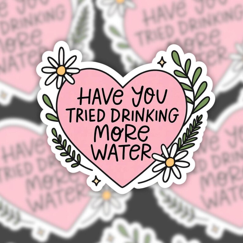 A vinyl sticker featuring a pink heart with the phrase “Have you tried drinking more water” in hand-lettered text. The heart is surrounded by white daisies, green leaves, and tiny sparkle doodles. The background is a blurred pattern of the same sticker.