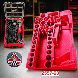 Può includere: Un organizer per utensili rosso con coperchio trasparente, contenente un set di bussole nere e un elettroutensile rosso e nero. Accanto, un porta utensili rosso con molteplici aperture circolari. Il testo "2557-20" è visibile.