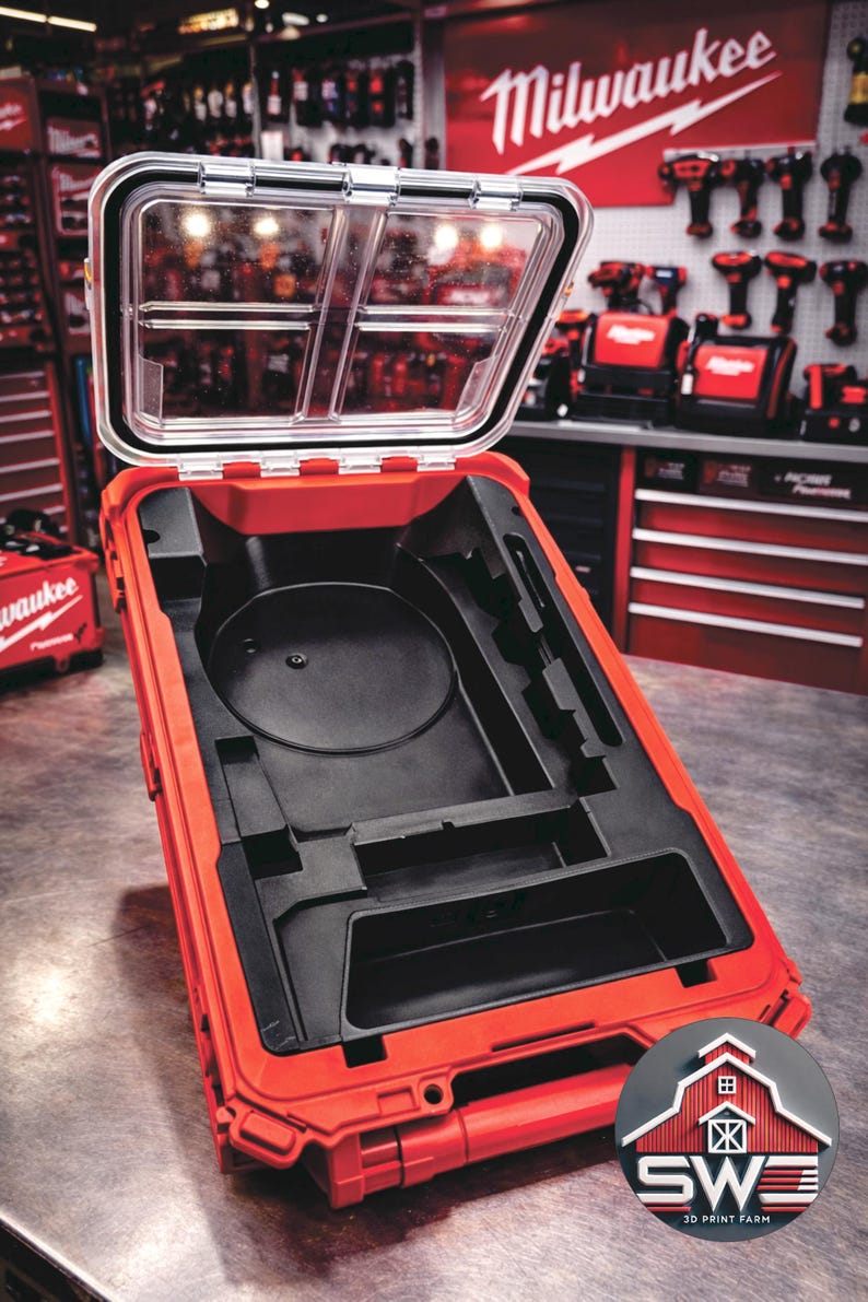 May include: Open red tool case with a clear lid, revealing a black interior with various compartments. The case is designed to hold tools and equipment. The Milwaukee logo is visible in the background.