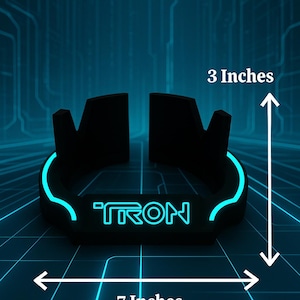 May include: Black, neon blue-edged bracelet with the word "TRON" in neon blue. The bracelet is 7 inches wide and 3 inches tall. The background is a blue grid pattern.