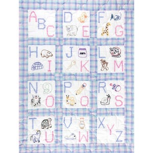 May include: A white alphabet quilt with a blue and pink gingham pattern. Each square features a letter of the alphabet and a corresponding image. The letters are embroidered in pink and the images are embroidered in blue.