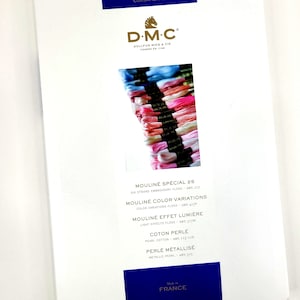 May include: DMC embroidery floss color card featuring a variety of colors, including pink, blue, and white. The card includes the brand name DMC, the company's founding date, and the names of different types of floss, including Moulin&eacute; Sp&eacute;cial 25, Moulin&eacute; Color Variations, Moulin&eacute; Effet Lumi&egrave;re, Coton Perle, and Perle M&eacute;tallis&eacute;.