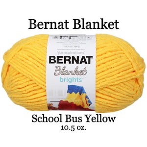 May include: A skein of bright yellow Bernat Blanket yarn with a white paper label. The label features the text Bernat Blanket, Yarnspirations, and School Bus Yellow. The yarn is 10.5 oz and made of 100% polyester. The label shows a small image of a blanket.