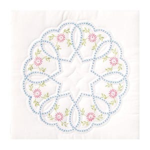 May include: A white fabric with a blue and green embroidered design of a circular floral pattern. The design features a repeating pattern of pink flowers with green leaves.