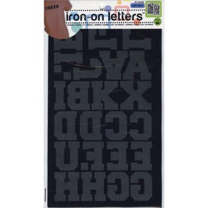 May include: A package of black iron-on letters in a block font. The package includes multiple sheets of letters, with the words "CHEER" and "iron-on letters" printed on the packaging. The letters are approximately 1 inch tall.