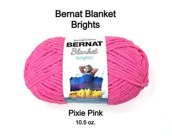 May include: A large ball of Pixie Pink Bernat Blanket Brights yarn. The label reads "Bernat Blanket brights" and features a person under a colorful blanket. The yarn weighs 10.5 oz.