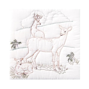 May include: White quilted square featuring an embroidered scene of deer in a natural setting. The design includes a buck with antlers, a doe, and a fawn resting on the ground. The embroidery uses brown thread for the deer and green for the foliage.