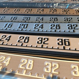 May include: Close-up of a set of four rulers with black numbers on a beige background. The rulers are marked in increments of four, starting at 8 and ending at 40. The rulers are made of a durable material and are perfect for measuring projects.