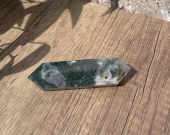May include: A green and white agate crystal point, also known as a wand, with a polished finish. The crystal has a unique pattern of green and white swirls.