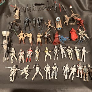K&ouml;nnte beinhalten: Eine Sammlung von Star Wars-Actionfiguren, darunter verschiedene Charaktere und Sturmtruppen. Die Figuren sind in verschiedenen Posen und weisen detaillierte Designs mit einer Reihe von Farben und Zubeh&ouml;r auf.