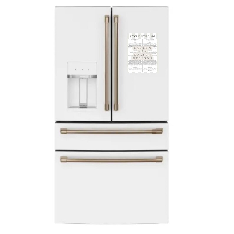 May include: A white refrigerator with a French door design, featuring brushed gold handles and a water dispenser. A magnet with the text "CYCLE SYNCING" and "LAUREN VAN DALSEN DESIGNS" is attached to the door.