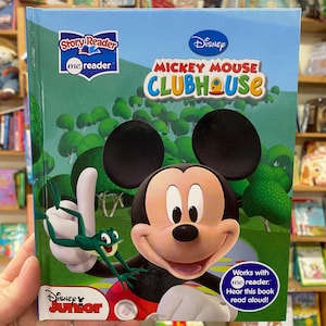 Può includere: Una copertina di libro con Mickey Mouse dello show di Disney Junior Mickey Mouse Clubhouse. La copertina è blu e verde con un'immagine di Mickey Mouse che sorride e una rana verde. Il libro fa parte della serie Story Reader me reader. Il testo sulla copertina recita "Disney Mickey Mouse Clubhouse" e "Funziona con me reader. Ascolta questo libro letto ad alta voce!"