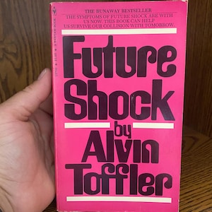 May include: A vintage paperback book titled "Future Shock" by Alvin Toffler. The cover is bright pink with bold, dark purple lettering. The book's cover includes text about the symptoms of future shock and the book's ability to help readers survive.