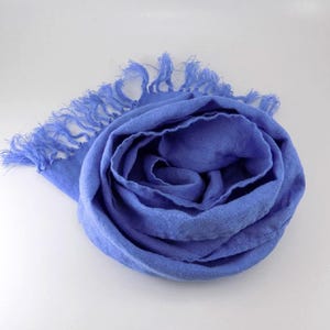 May include: A soft, blue linen scarf with fringed edges. The scarf is folded into a rose shape.