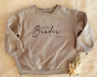 May include: A light gray sweatshirt with the text "großer Bruder 2025" printed in black.