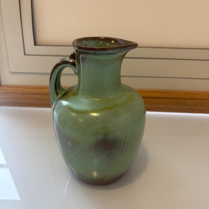 May include: A set of three ceramic mugs with a speckled, matte finish. The mugs are in shades of cream, light grey, and dark grey. Each mug has a simple, minimalist design, ideal for coffee or tea.