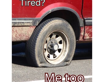 May include: A flat tire on a red vehicle. The tire is deflated and resting on the asphalt. Text on the image reads "Tired?" above the tire and "Me too" below it.