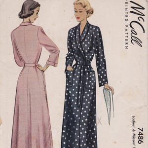 May include: A McCall printed pattern envelope for a robe, number 7486. The illustration shows two floor-length robes: one solid light pink with long sleeves and a collar, and one dark navy blue with white polka dots, featuring a belt and pockets.